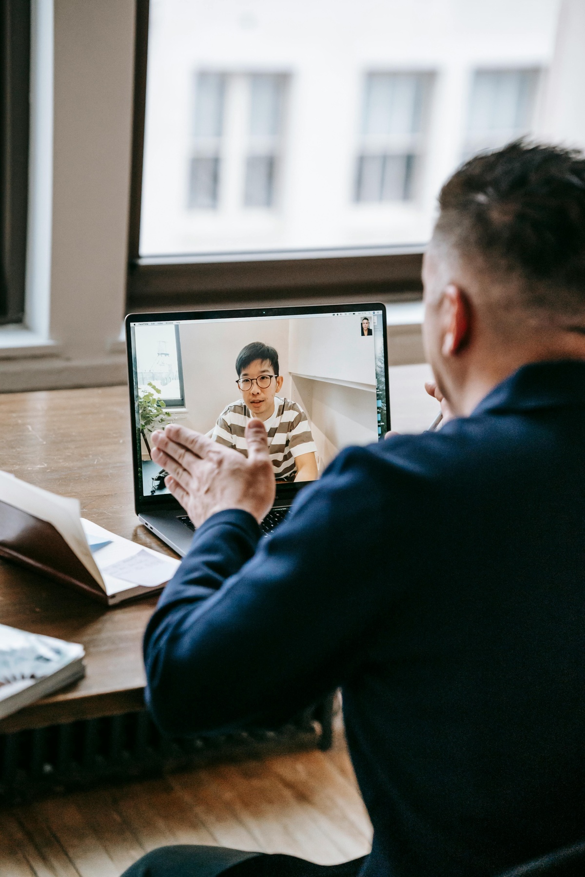 A program coach on a video call, gesturing during conversation. Coaching is the through-line of the program.
