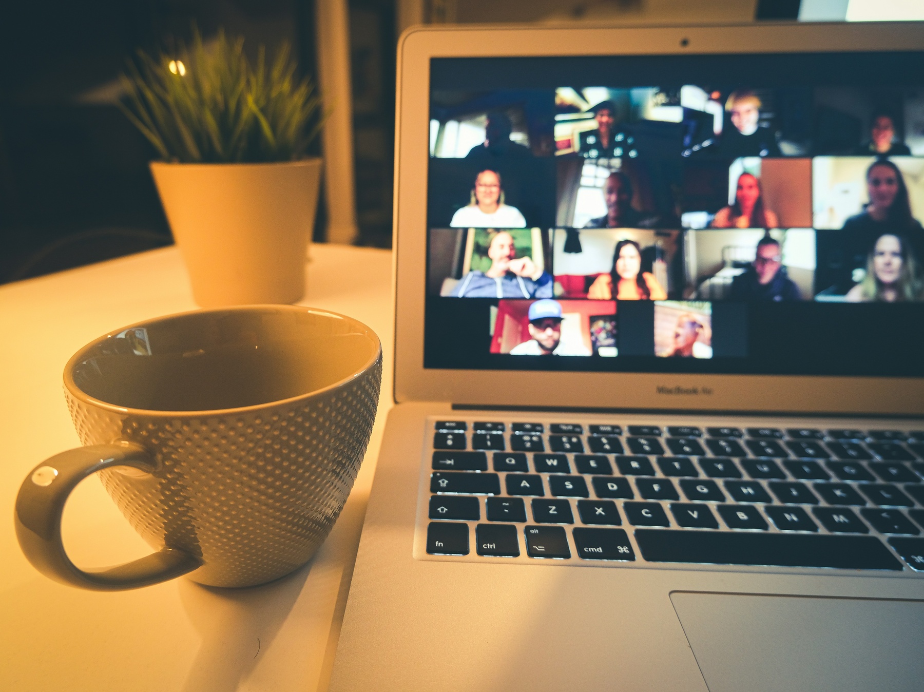 A group video call viewed across a desk with a mug. The cohort element of the program.